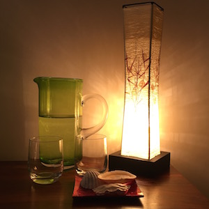 Paper lamp giving a warm glow over a green glass pitcher of water.